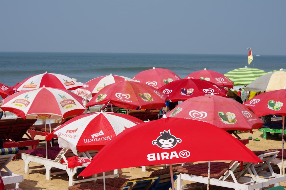 a bunch of red and white umbrellas on a beach