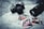 A vintage camera rests on a black and white map alongside photographs of a red sports car, featuring close-up shots of the car's interior and exterior. A large camera lens is positioned nearby, and the items are arranged in an artistic, nostalgic style.