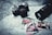 A vintage camera rests on a black and white map alongside photographs of a red sports car, featuring close-up shots of the car's interior and exterior. A large camera lens is positioned nearby, and the items are arranged in an artistic, nostalgic style.