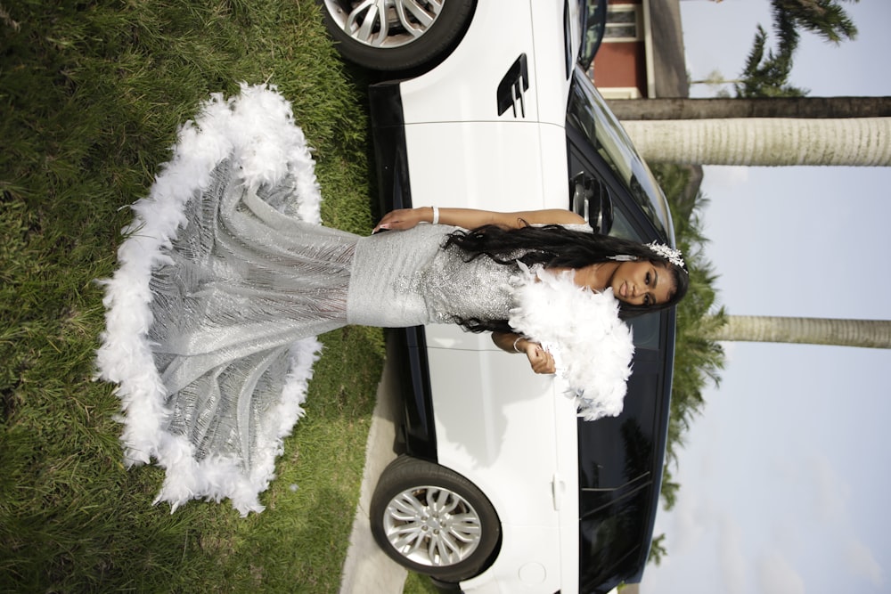 a woman in a dress standing in front of a car