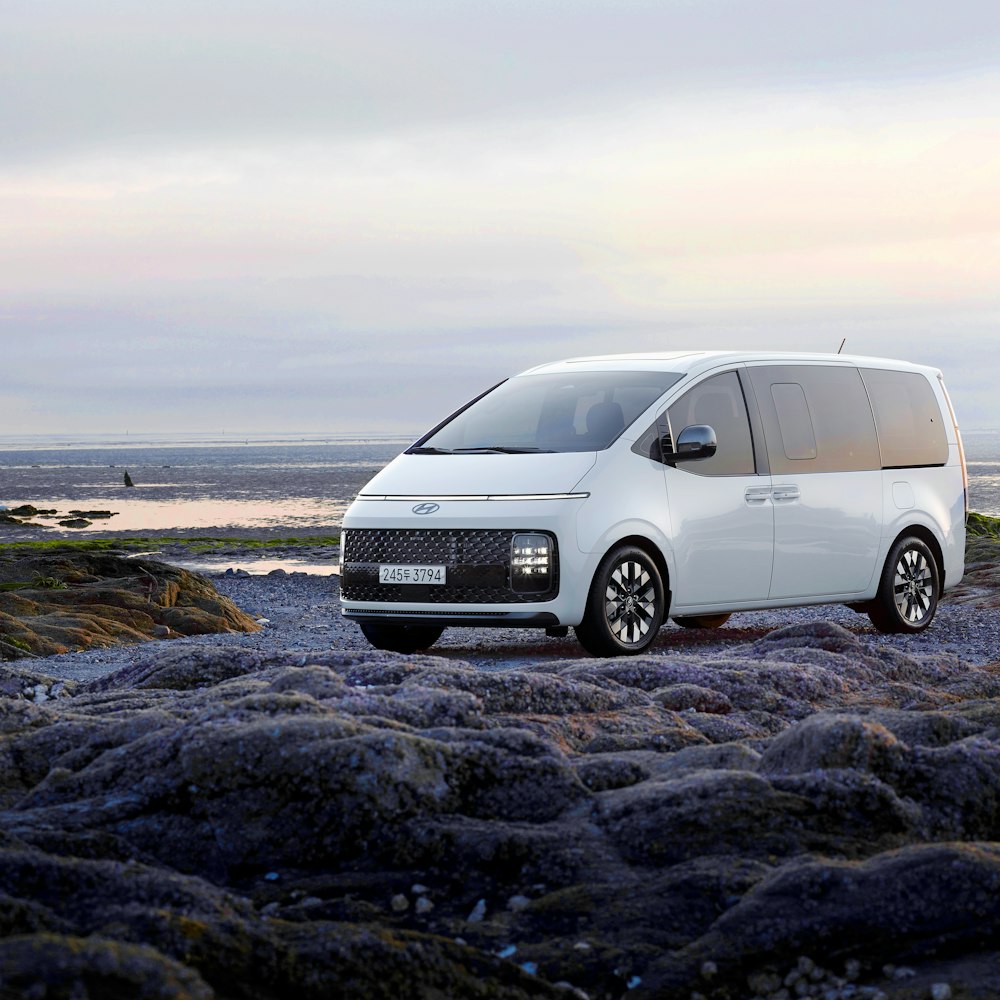 a white van parked on top of a rocky beach