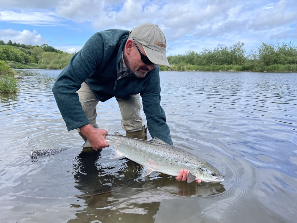 Ein Mann, der einen Fisch in einem Gewässer hält