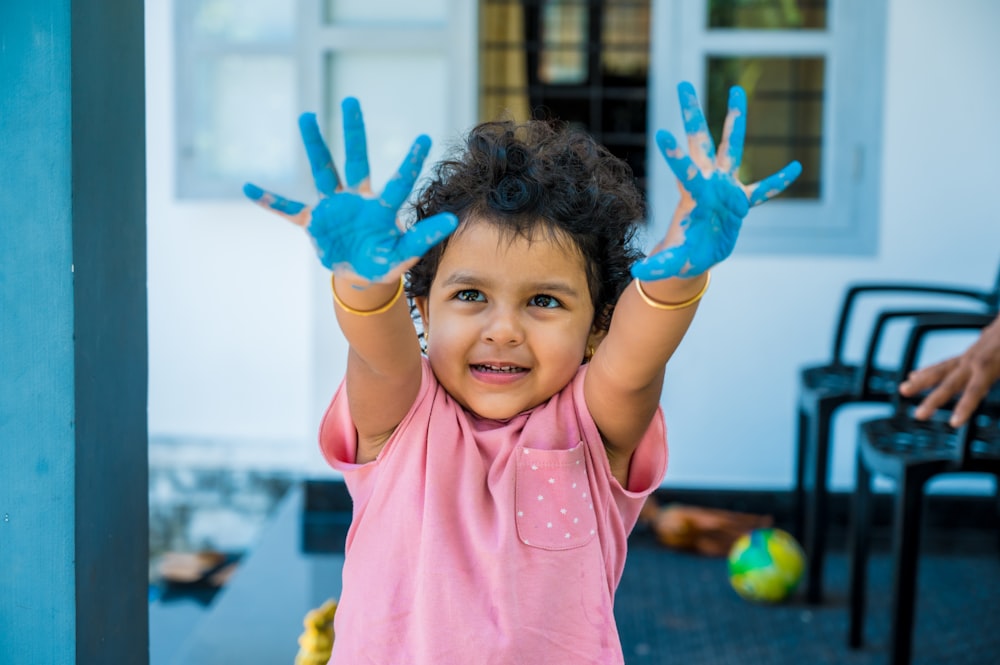 Une petite fille avec ses mains peintes en bleu