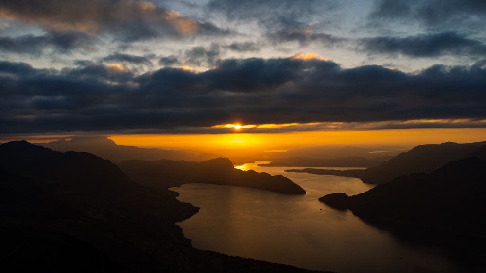 the sun is setting over the mountains and water