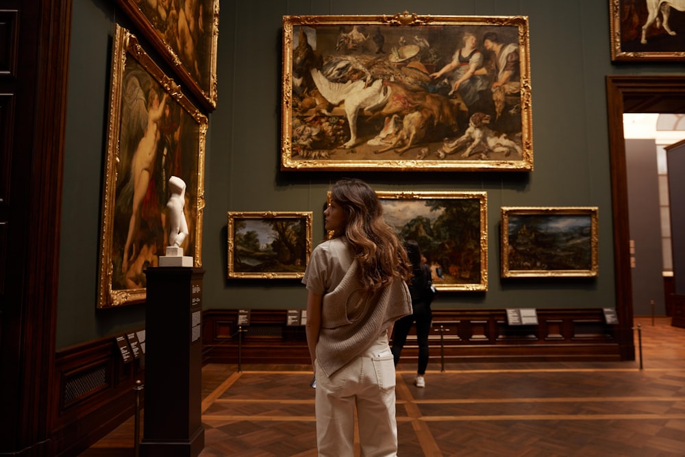 uma mulher olhando para pinturas em um museu