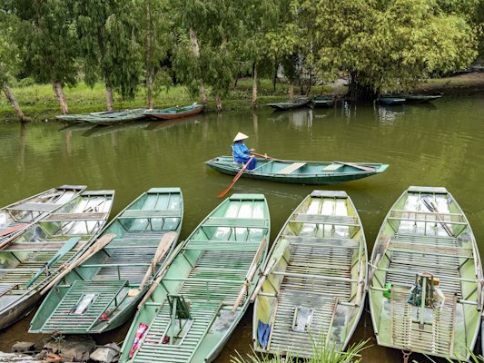 A group of small boats floating on top of a river — Ninh Bình, Vietnam