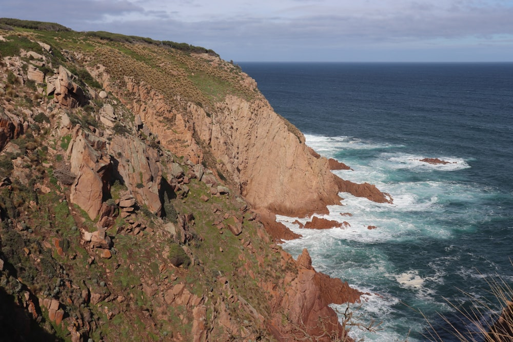 a rocky cliff overlooks the ocean on a cloudy day