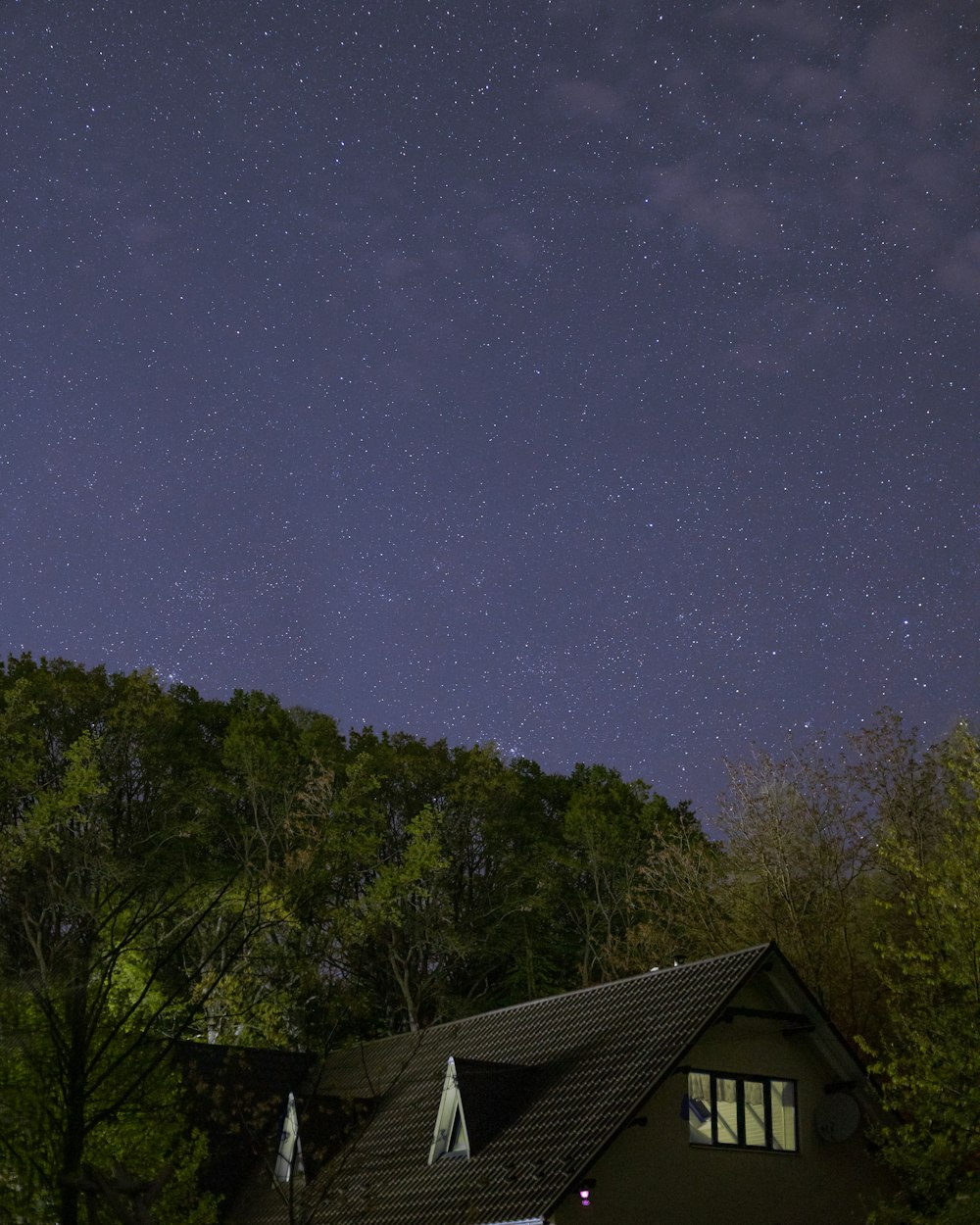 the night sky with stars above a house