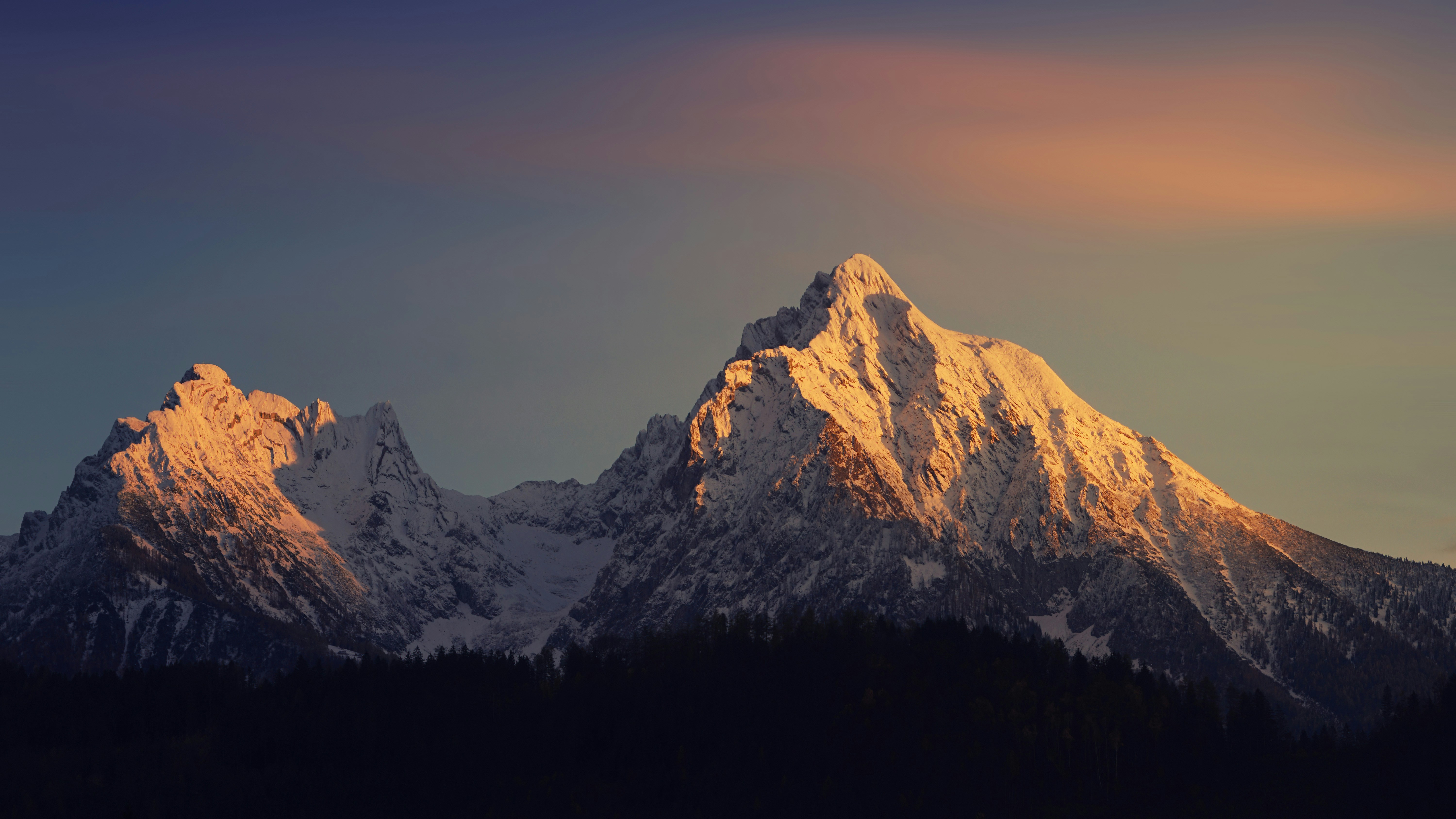 a snow covered mountain with trees in the foreground