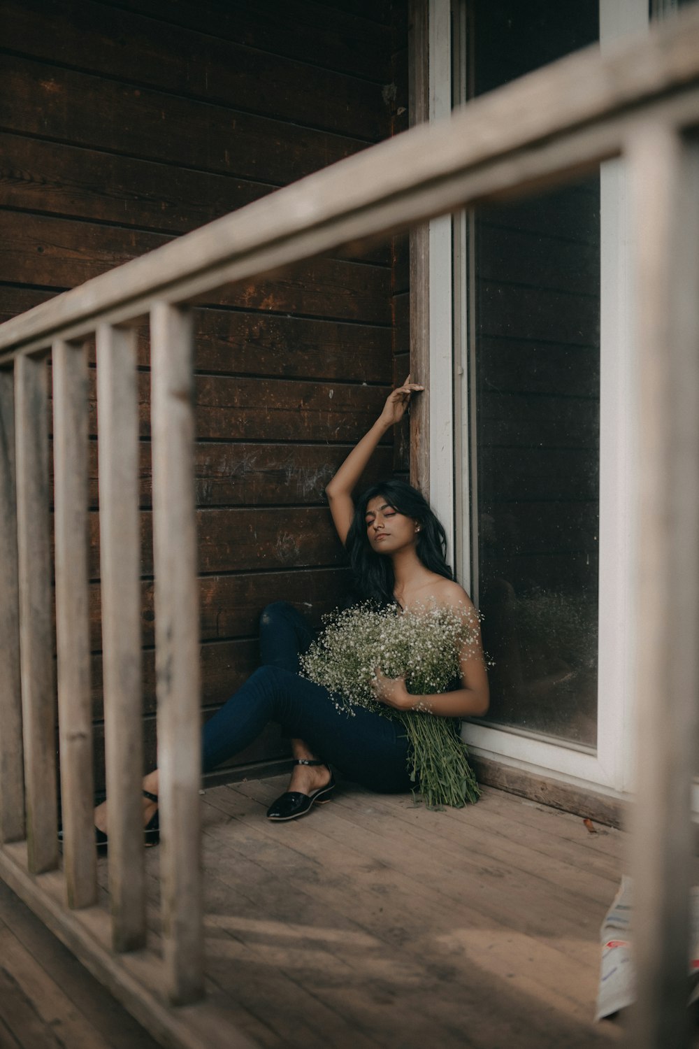 a woman sitting on a porch holding a bunch of flowers