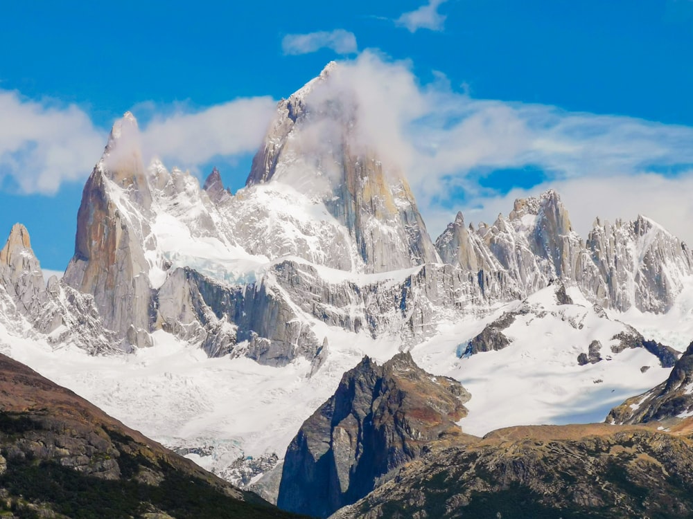 a snow covered mountain range with clouds in the sky