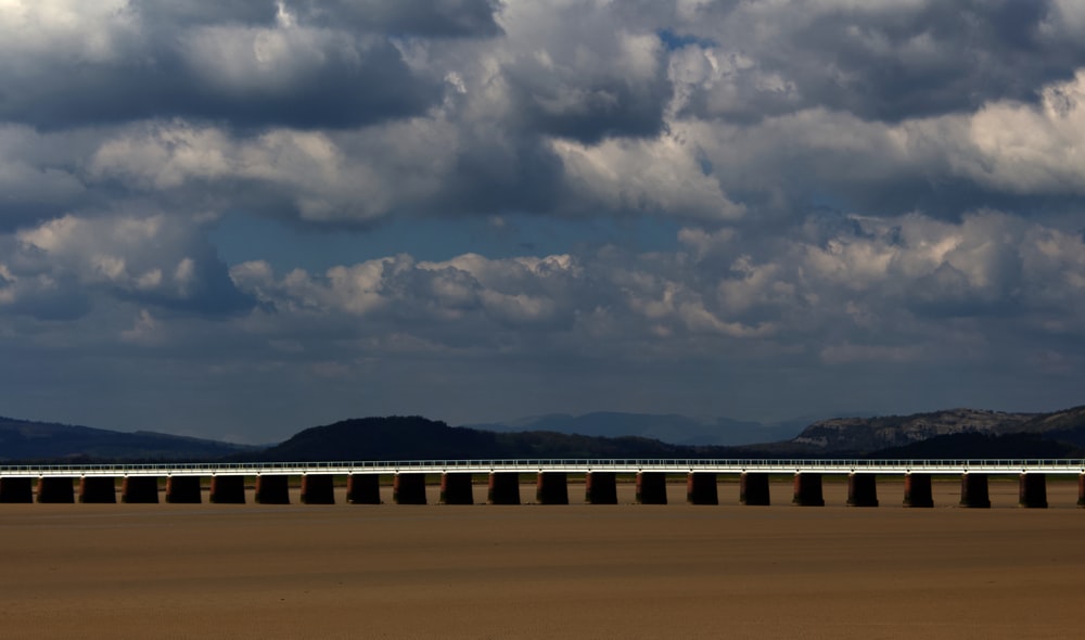 a train traveling across a sandy beach under a cloudy sky