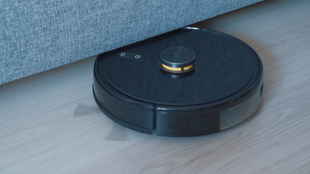 un robot aspirateur noir sur un plancher en bois