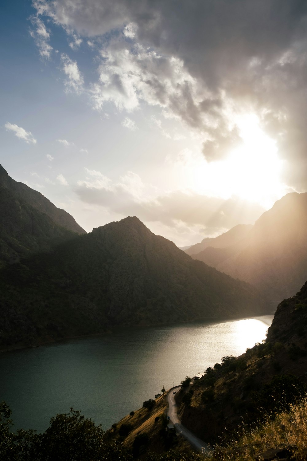 the sun is shining over a mountain lake