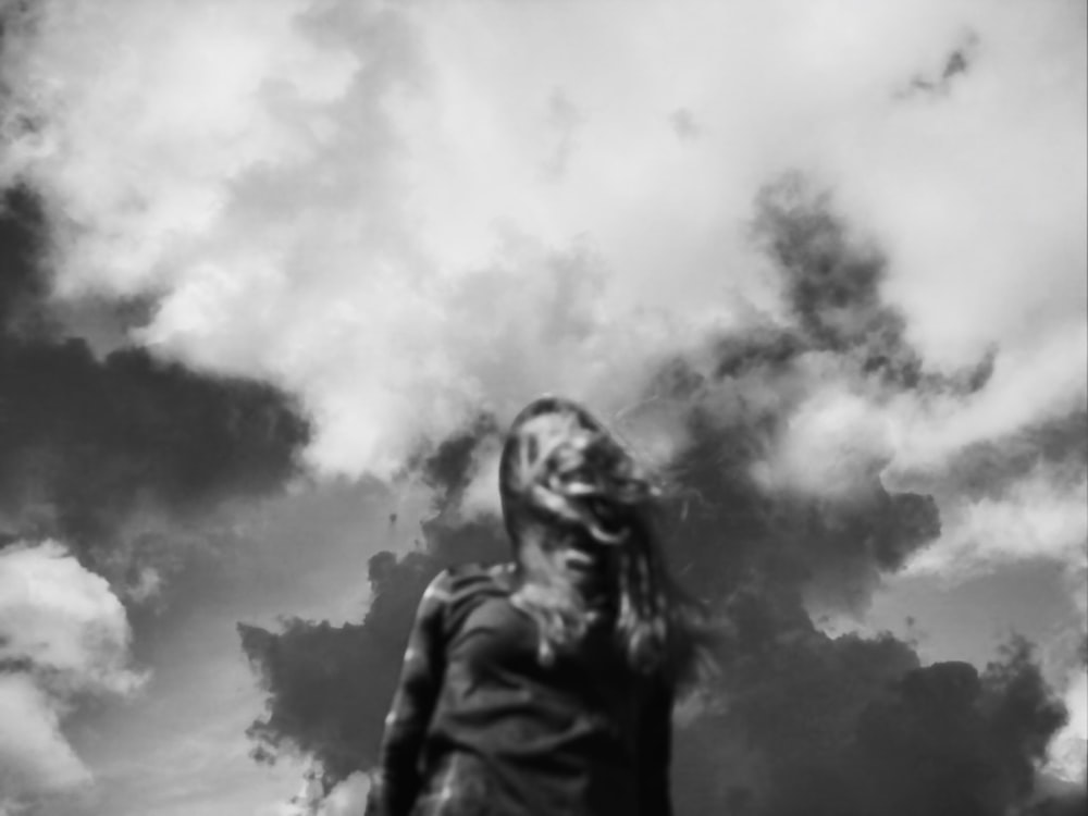 a woman standing in front of a cloudy sky