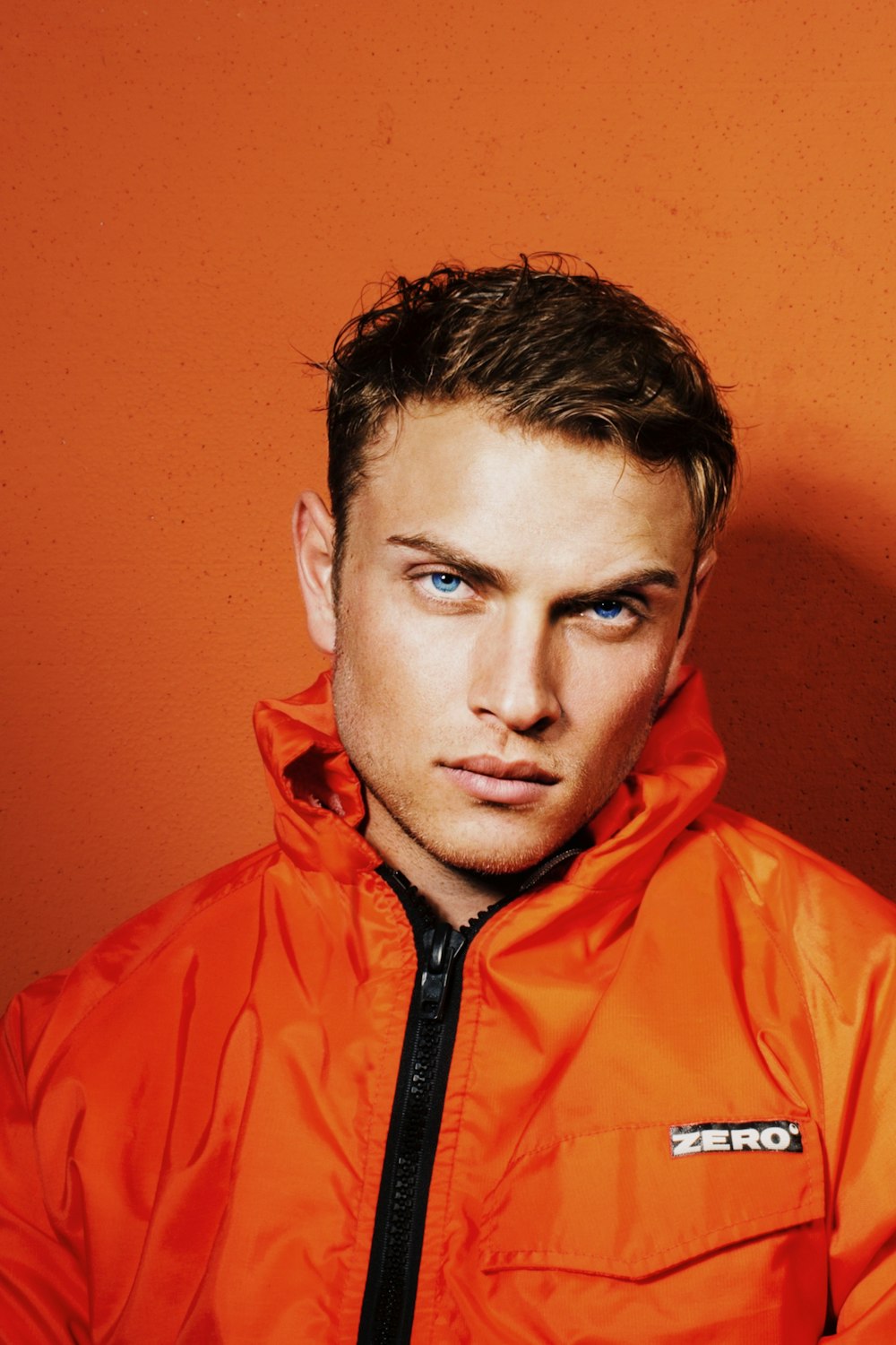 a man in an orange jacket poses for a picture