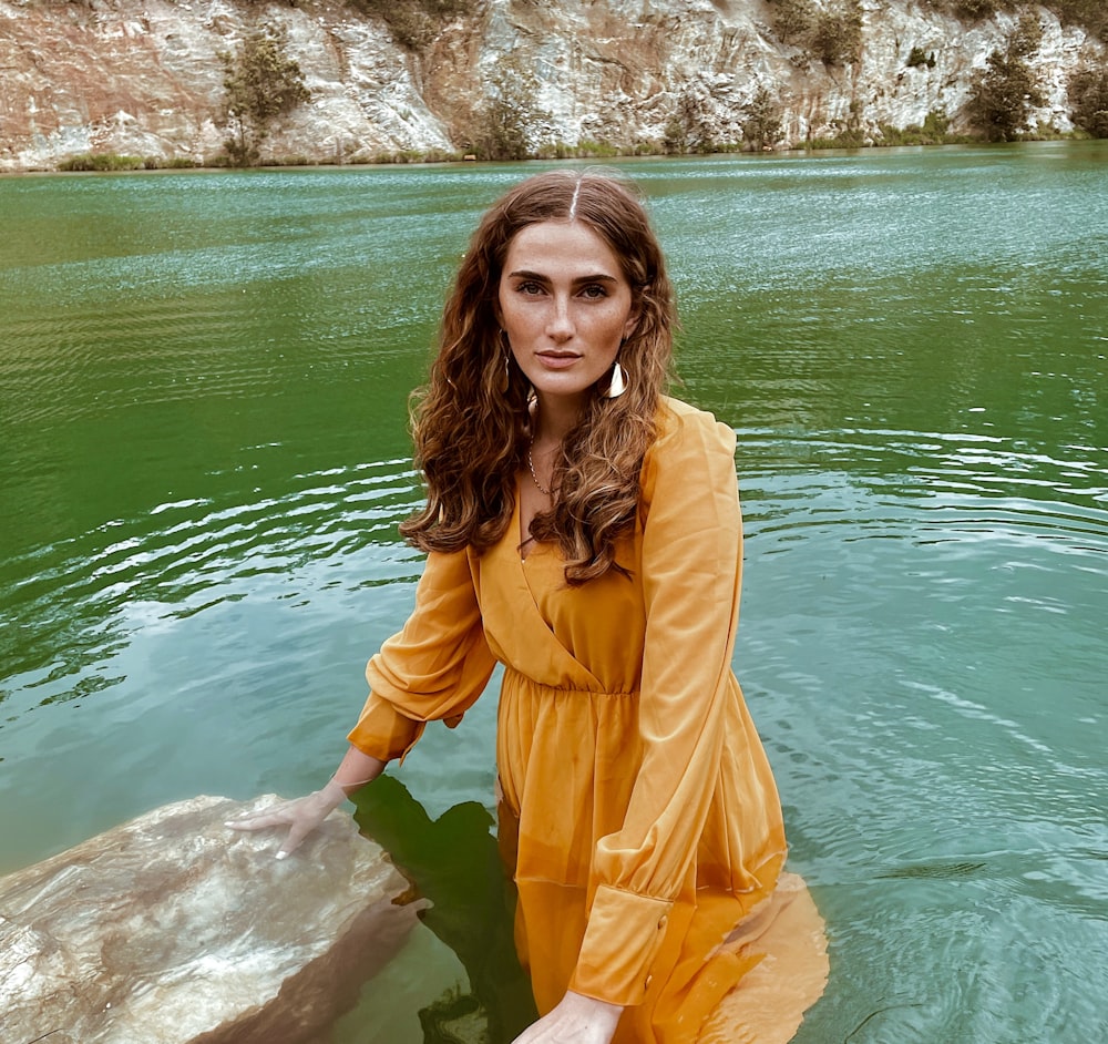 a woman in a yellow dress standing in a body of water