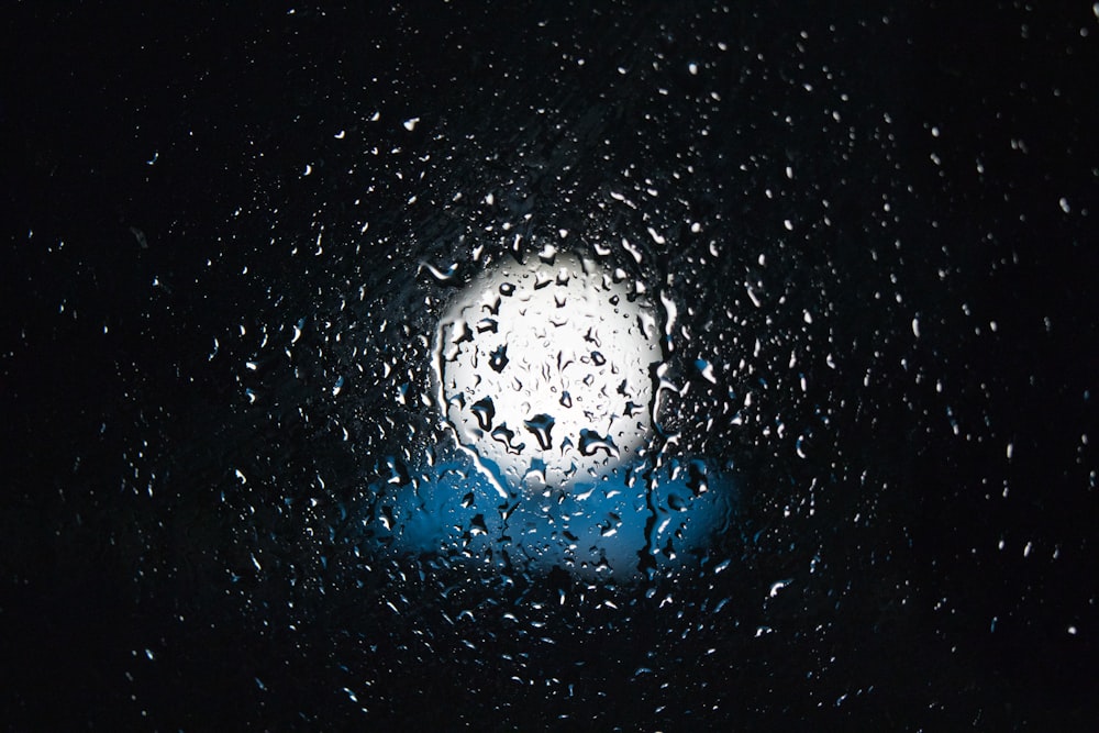 gotas de chuva em uma janela com uma luz azul no fundo