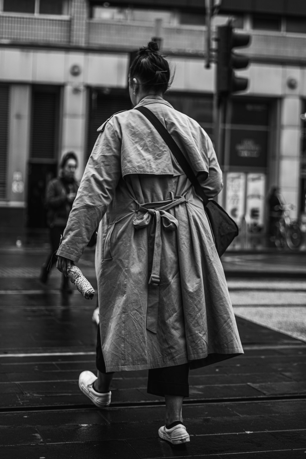 a woman in a trench coat walking down the street