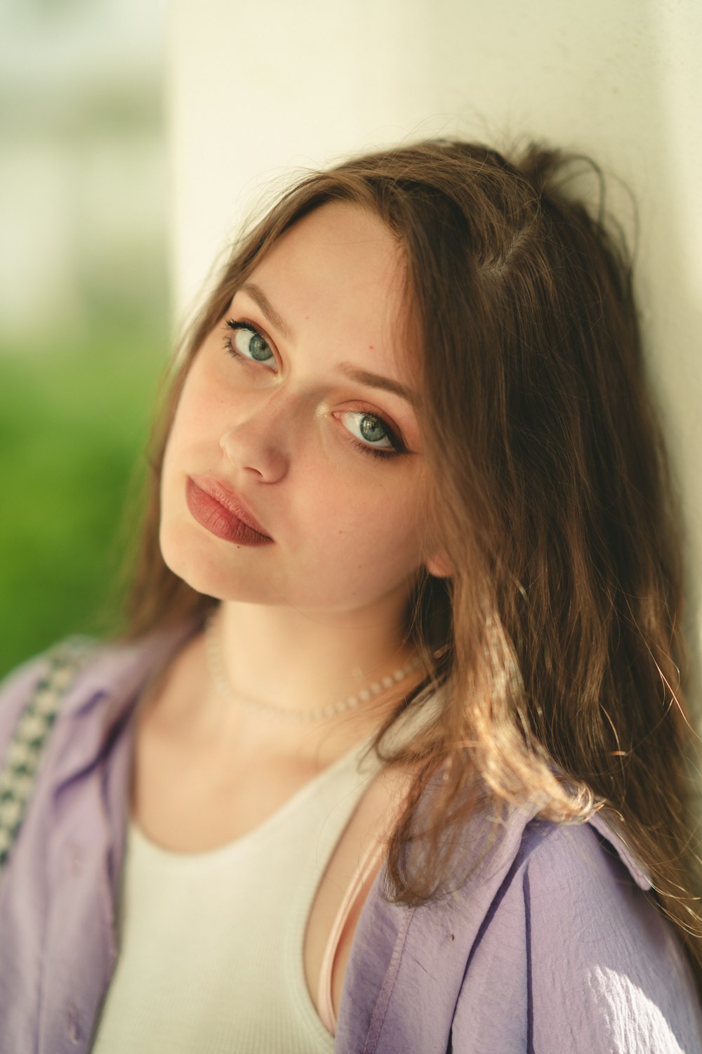 a woman leaning against a wall and looking at the camera