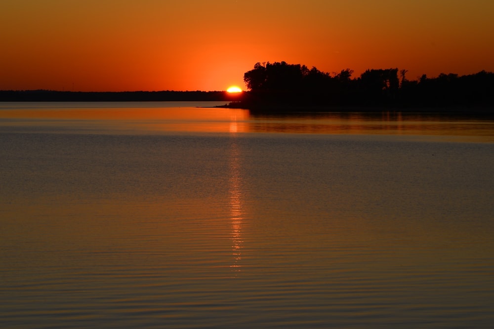 un grand plan d’eau avec un coucher de soleil en arrière-plan