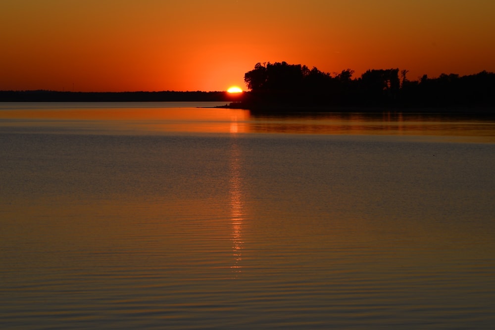 Un grande specchio d'acqua con un tramonto sullo sfondo