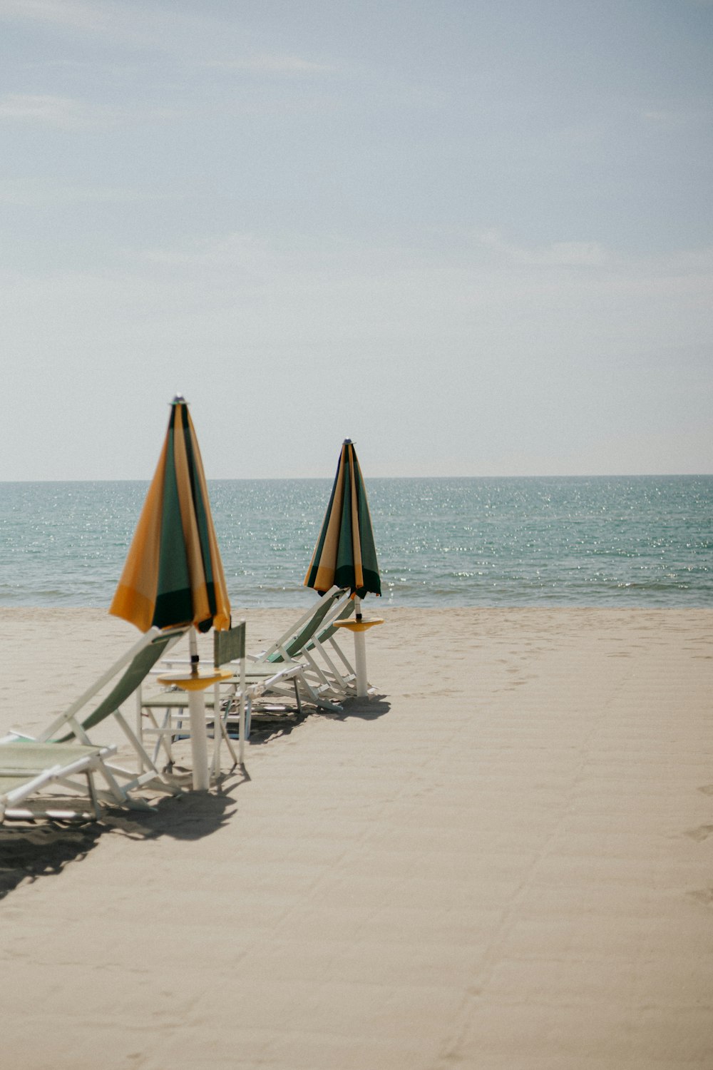 a row of lawn chairs sitting on top of a sandy beach