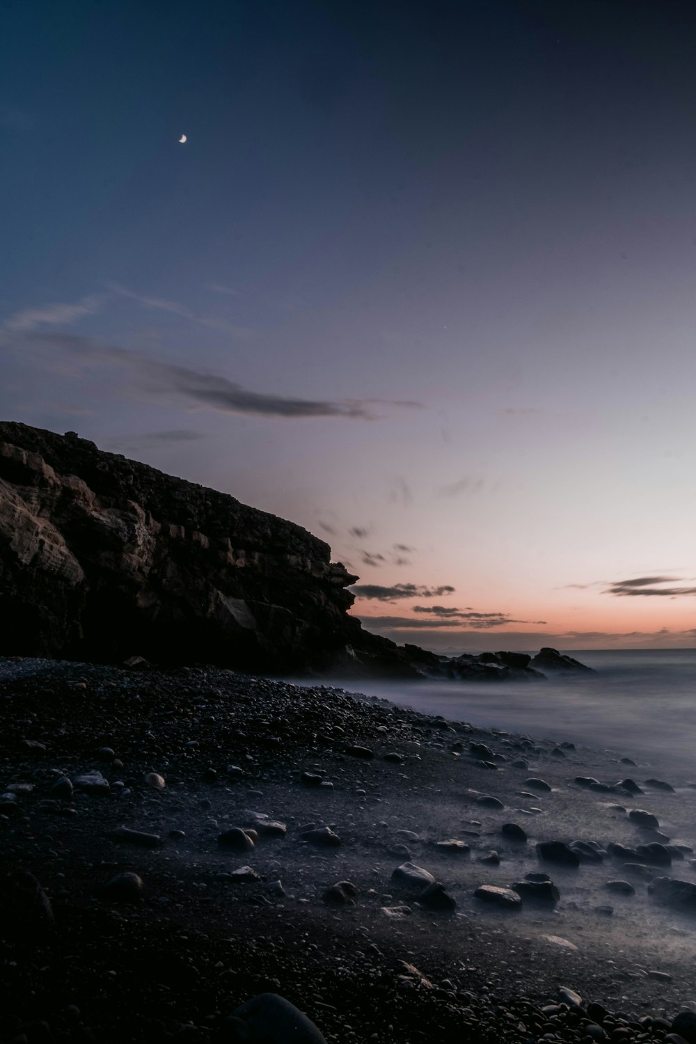 a beach with rocks and water at sunset