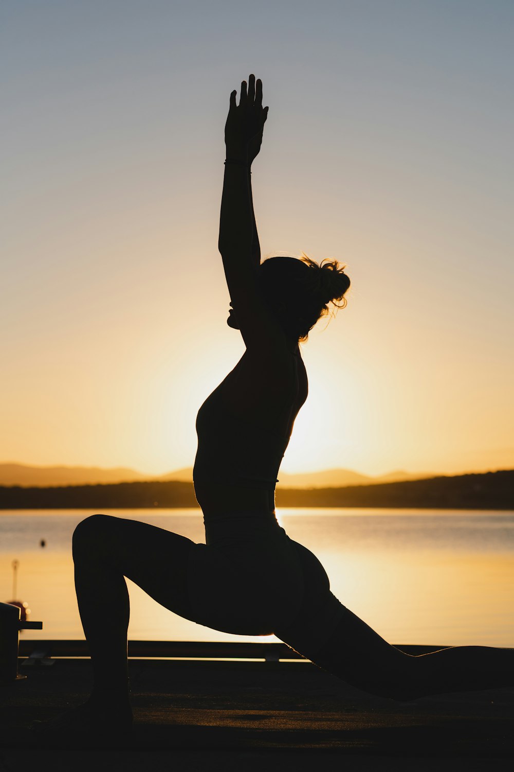 a woman doing a yoga pose in front of a body of water