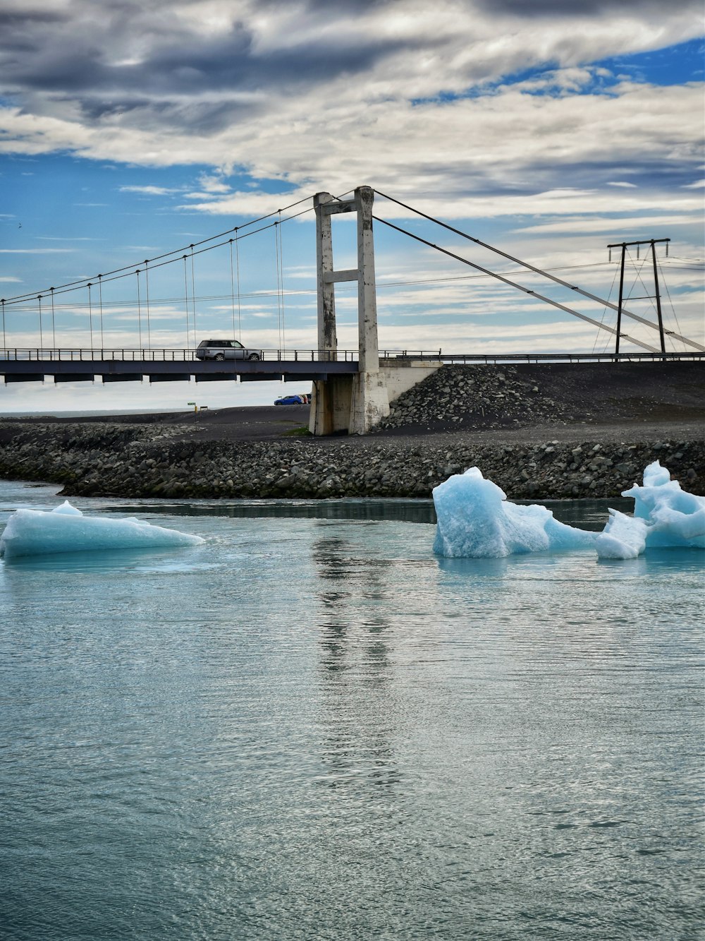 icebergs floating in the water near a bridge