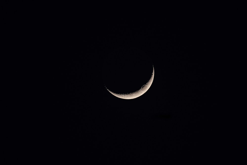 a crescent moon is seen in the dark sky