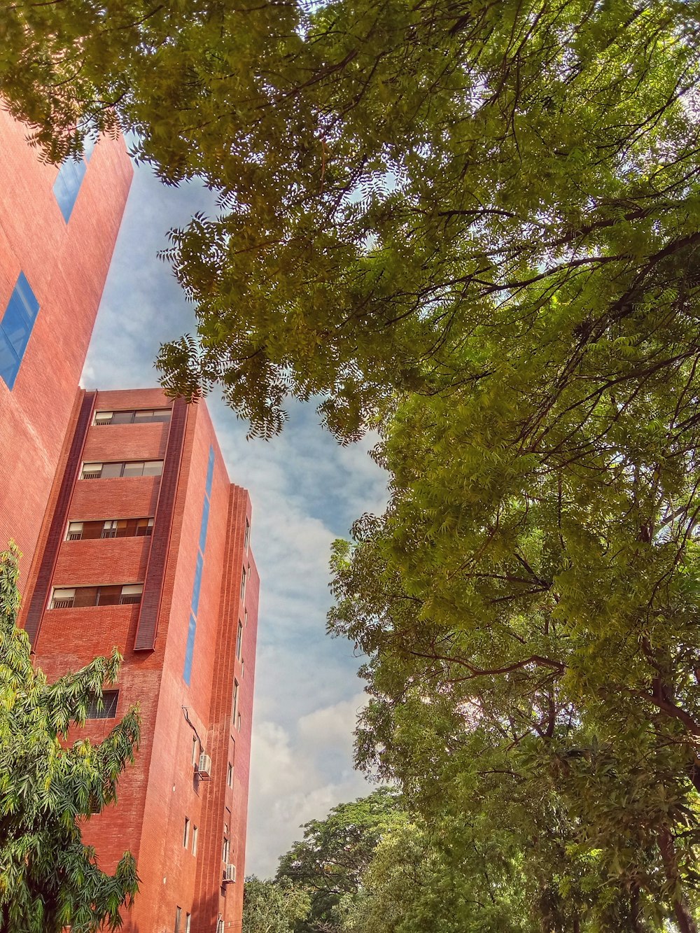 a tall red building sitting next to a lush green forest