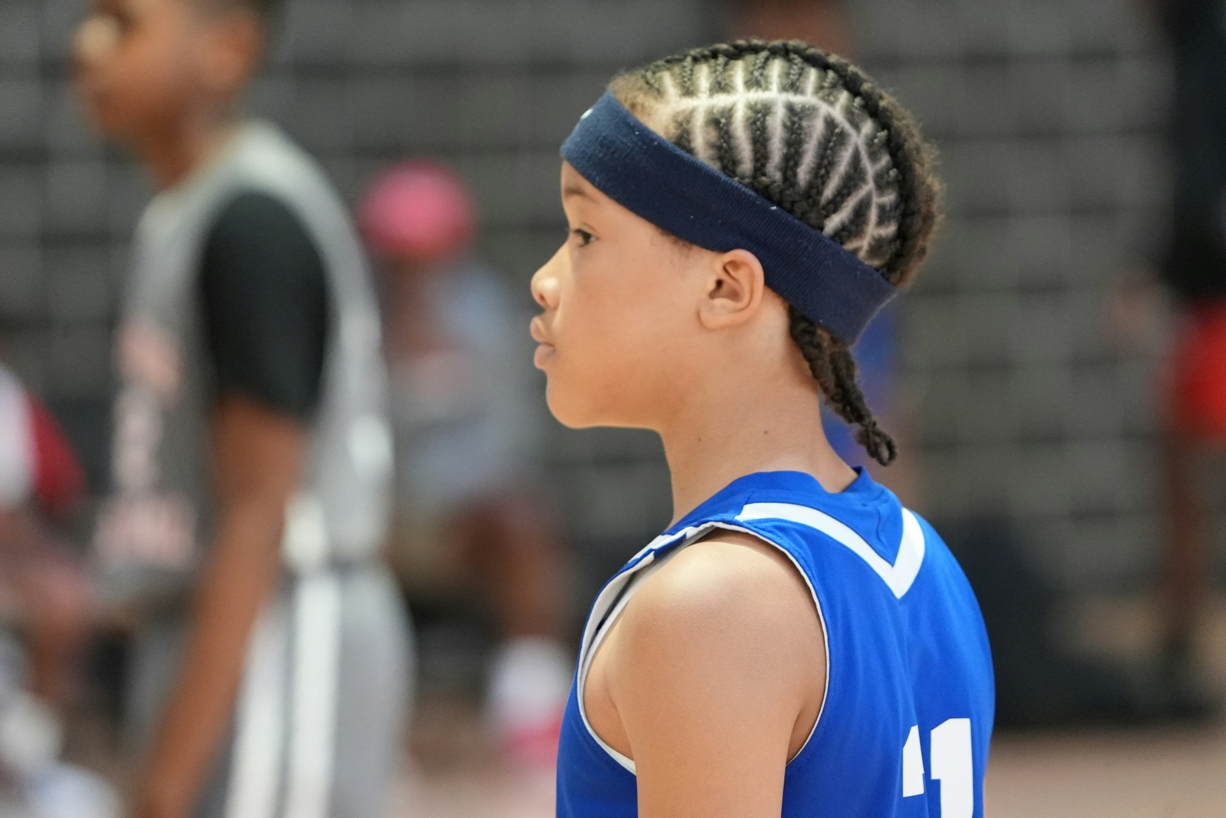 Seorang anak laki-laki berkaus biru sedang bermain bola basket