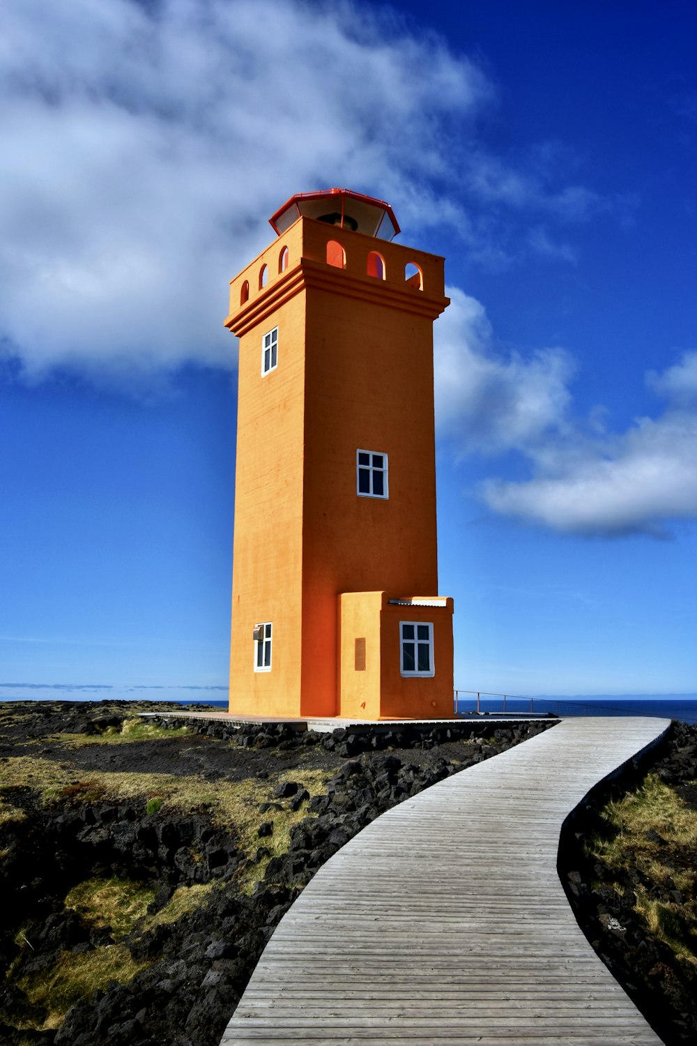 a walkway leading to a tall orange tower