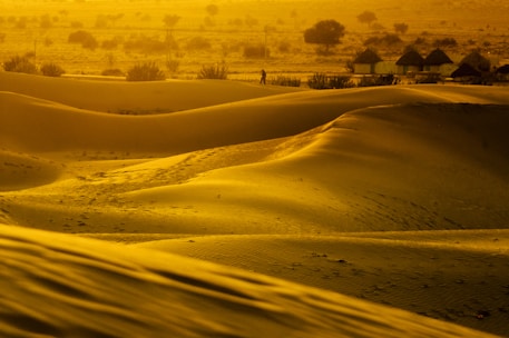 A winding desert path at sunset, with warm terracotta hues casting long shadows over sand dunes.