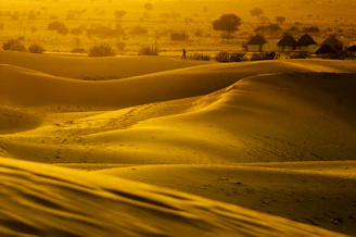 Golden desert dunes under a vibrant sunset in Dubai, with a luxury caravan silhouette.