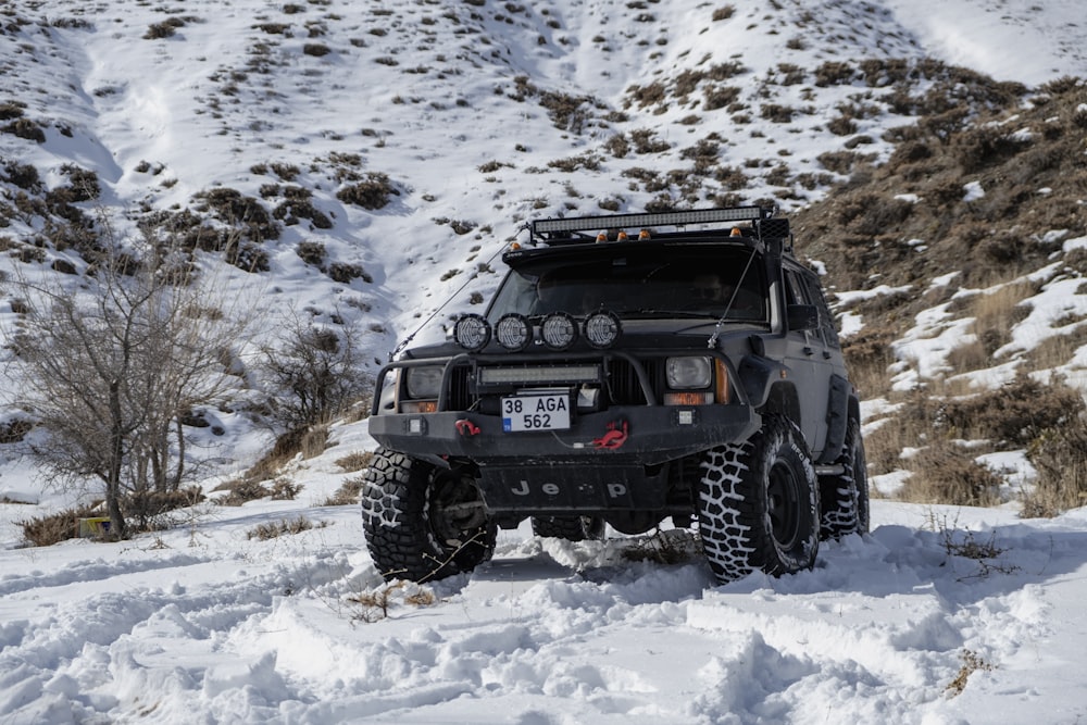 a black vehicle driving on a snowy road