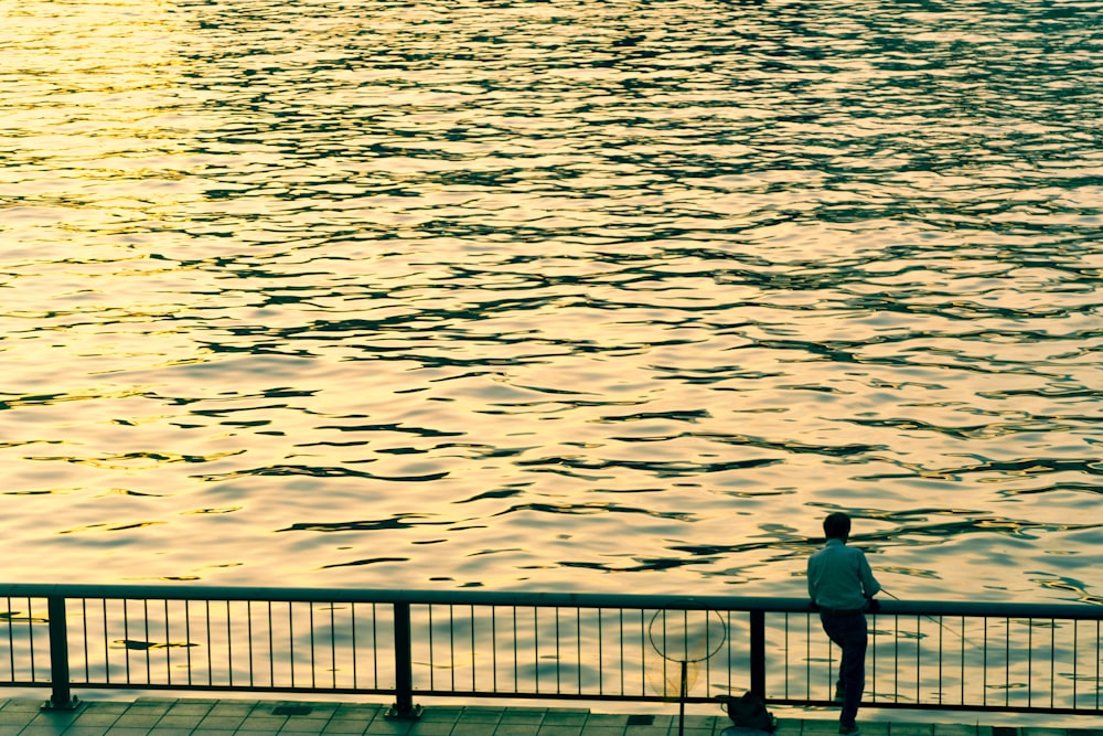 a man standing on a pier next to a body of water