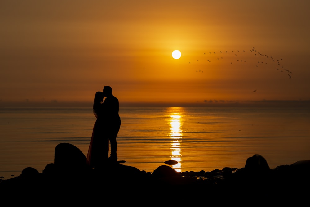 a couple of people standing on top of a beach