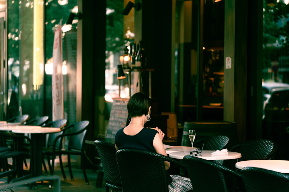 a woman sitting at a table outside of a restaurant
