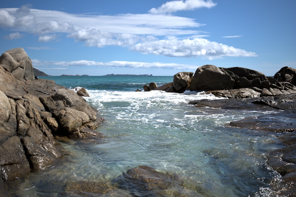 a body of water surrounded by rocks under a blue sky