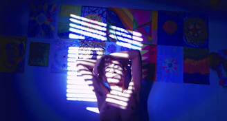 a woman standing in front of a window with her hands on her head