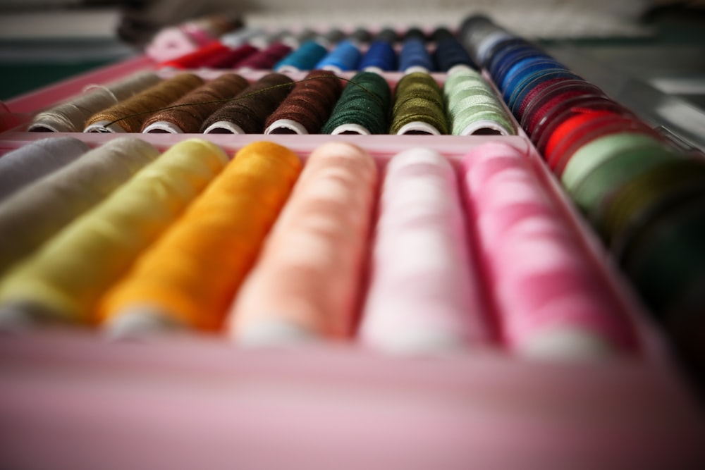 a row of different colored spools of thread