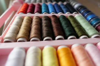 a pink box filled with different colored spools of thread