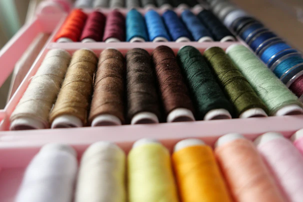 a pink box filled with different colored spools of thread