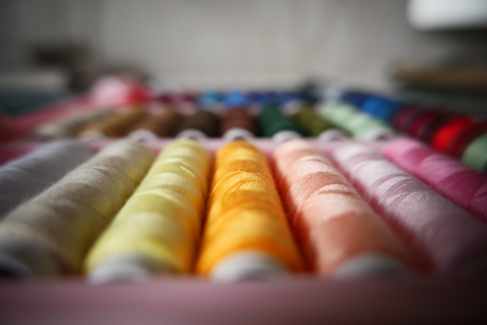 a row of different colored spools of thread
