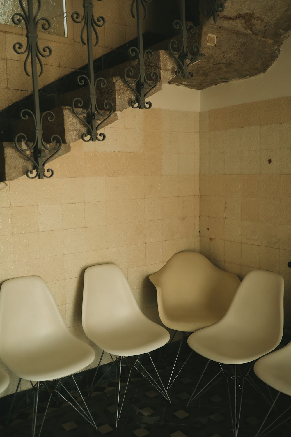 four white chairs are lined up against a wall
