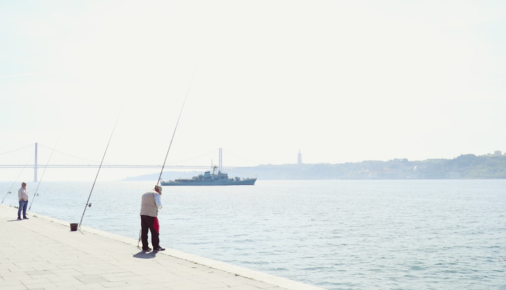 a man standing on a pier holding a fishing pole