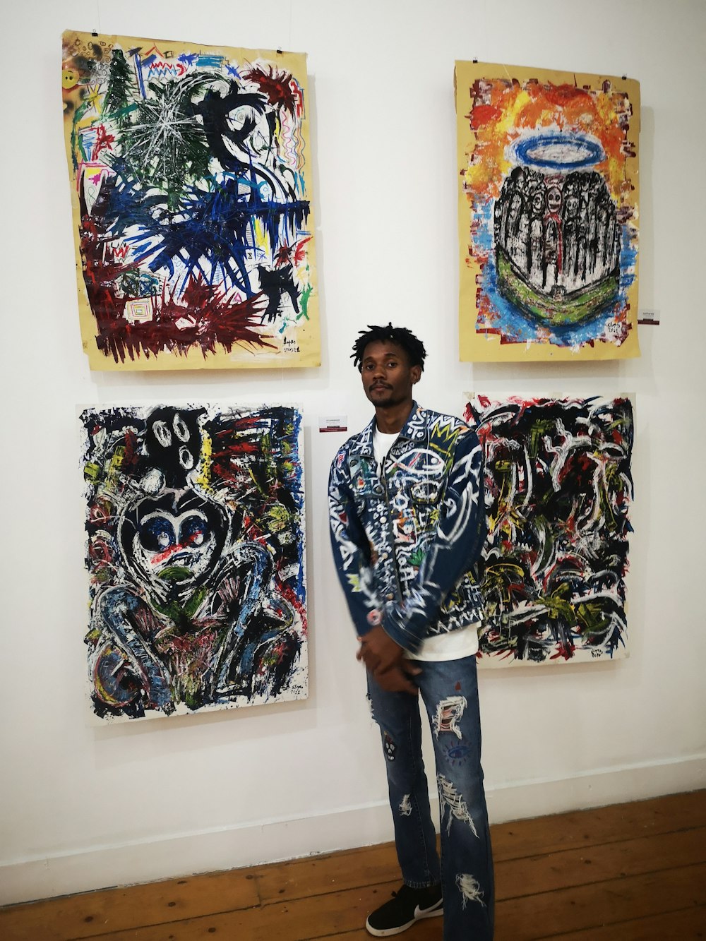 a man standing in front of two paintings