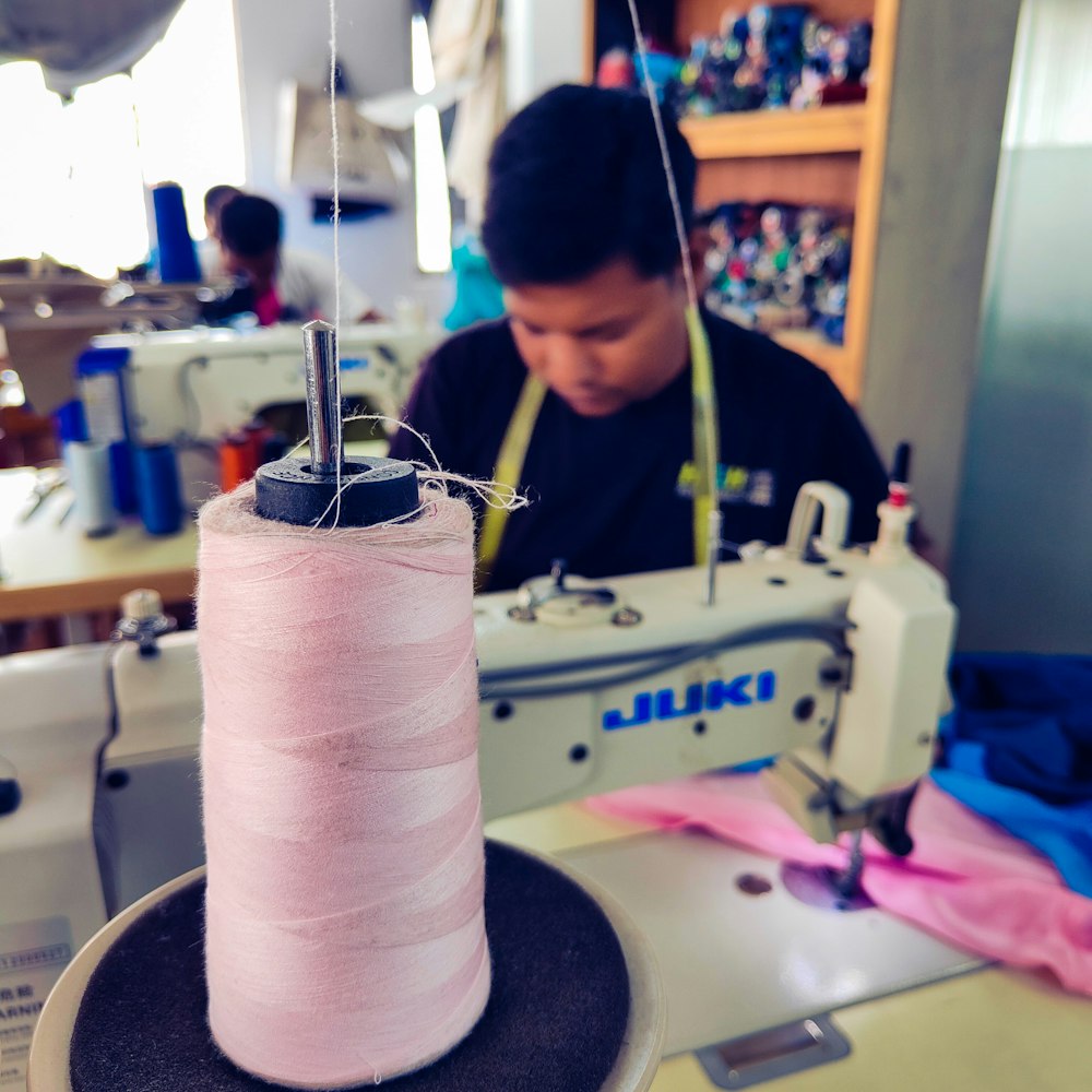 a man working on a pink thread on a sewing machine